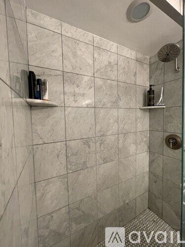 A bathroom with a marble tile wall and a glass shower door.