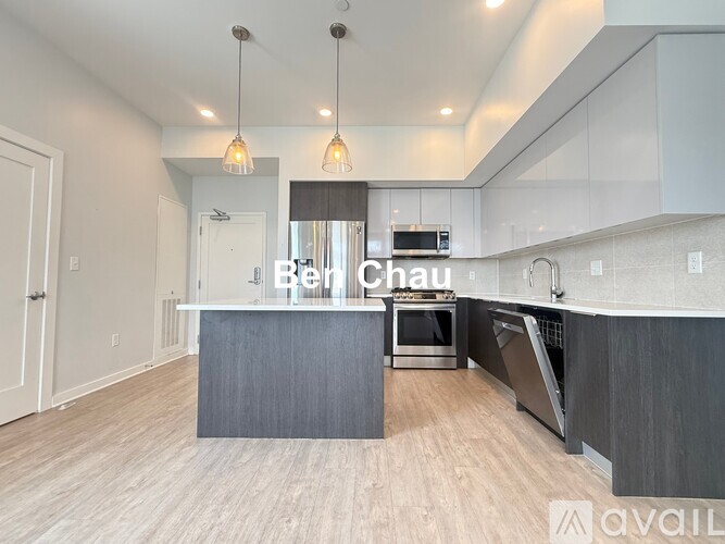 A modern kitchen with a large island and pendant lights.