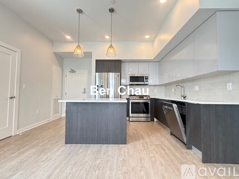 A modern kitchen with a large island and pendant lights.