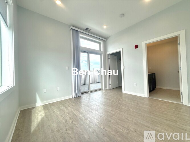 A spacious room with a sliding glass door leading to a balcony.