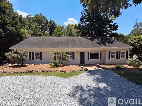 A house with a grey roof and a gravel driveway in front.