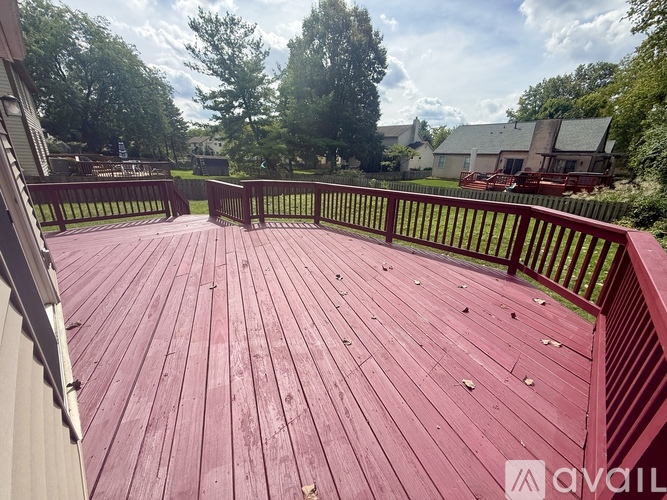 A wooden deck with a railing and trees in the background.