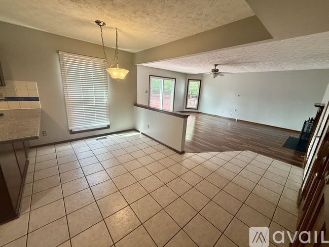 A spacious room with tiled flooring and a ceiling fan.