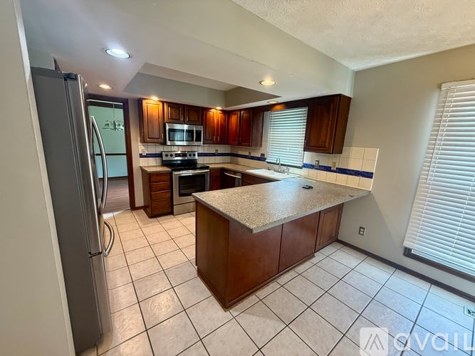 A kitchen with a refrigerator, microwave, oven, and sink.