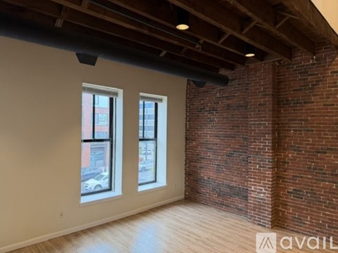 A room with a brick wall and two windows.