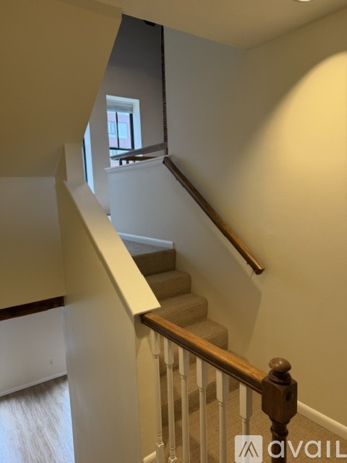 A staircase with a wooden handrail and white walls.