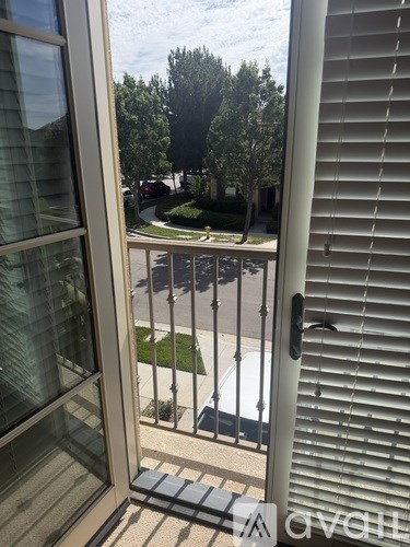 A view from a window looking out to a street with a car and trees.