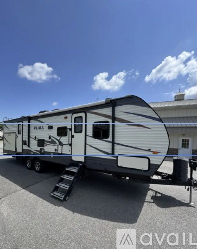A white RV with the word "PLM" on the side is parked on a paved area.