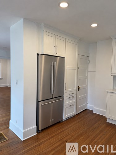 A stainless steel refrigerator in a kitchen with white cabinets.