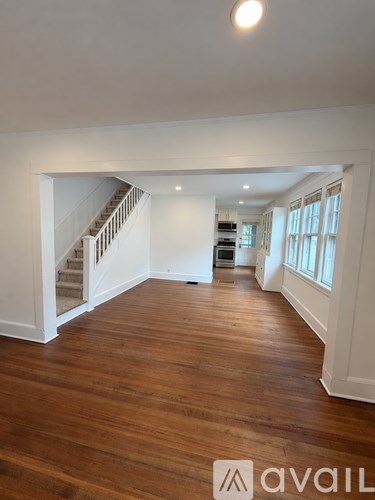 A spacious room with wooden floors and a staircase.
