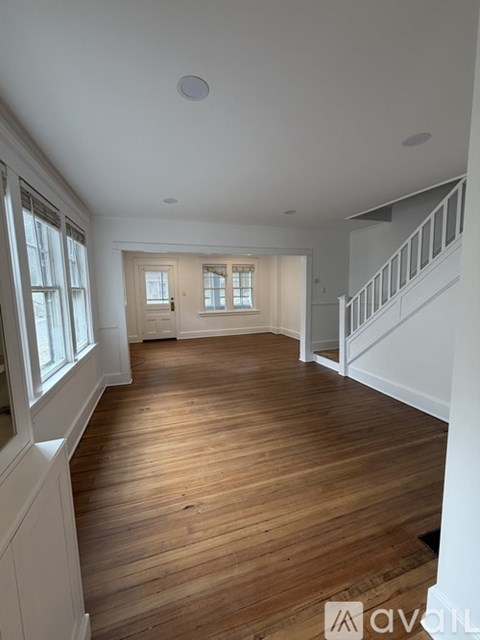 A spacious room with wooden floors and white walls.
