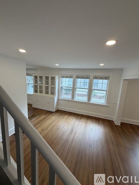 A room with wooden floors and a staircase leading to the next level.