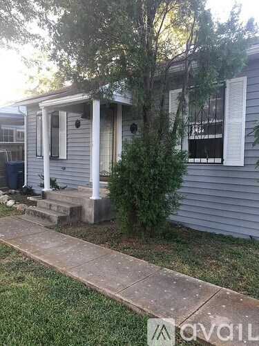 A house with a porch and a tree in front.