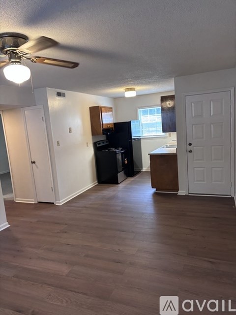 A room with a ceiling fan and wooden flooring.