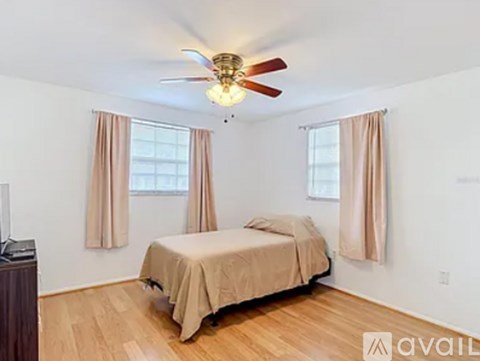 A bedroom with a bed, a ceiling fan, and a window with curtains.