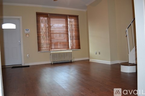 A room with wooden floors and a window with blinds.