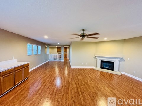 A spacious living room with wood flooring and a fireplace.