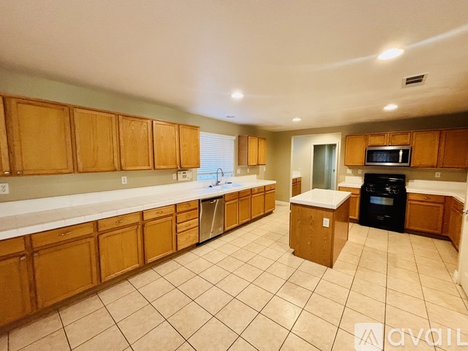 A kitchen with wooden cabinets and a black dishwasher.