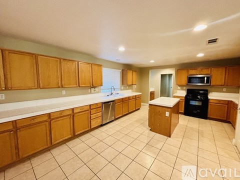 A kitchen with wooden cabinets and a black dishwasher.