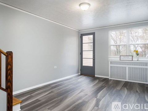 A room with a grey door and a window with a view of trees outside.