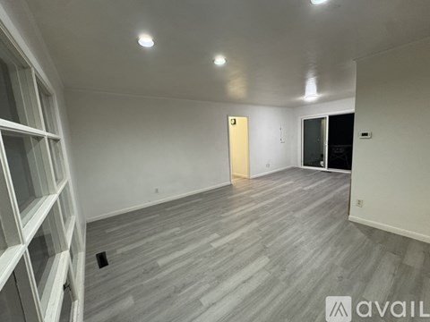 A room with wooden flooring and white walls, with a door in the middle of the room.