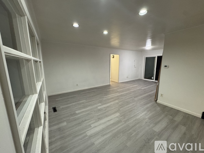 A room with a grey floor and white walls is available for rent.