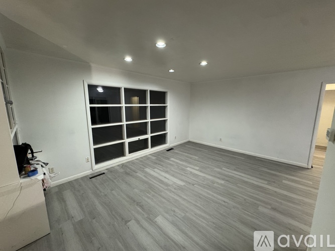 A spacious room with wooden flooring and a large window with multiple panes.