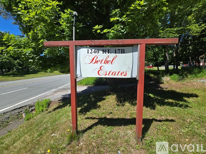A sign for Bethel Estates stands in a grassy area by a road.
