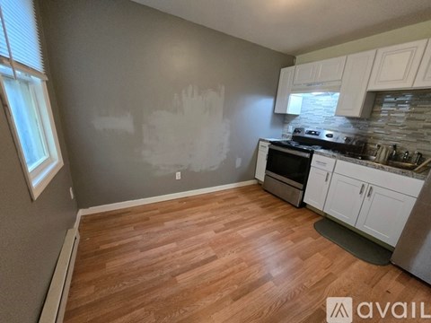 A kitchen with wooden floors and white cabinets is available for rent.