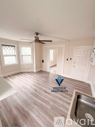 A Vodock Apartments sign is on a wall in a spacious room with wood flooring and a ceiling fan.