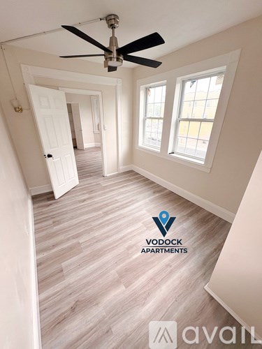 A room with a ceiling fan and a logo of Vodock Apartments.