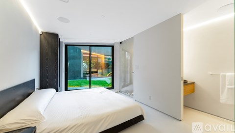 A bedroom with a large bed and a balcony with a view of a building.