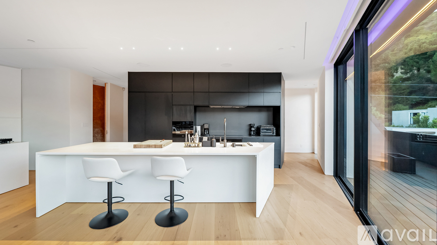 A modern kitchen with white chairs and a bar area.