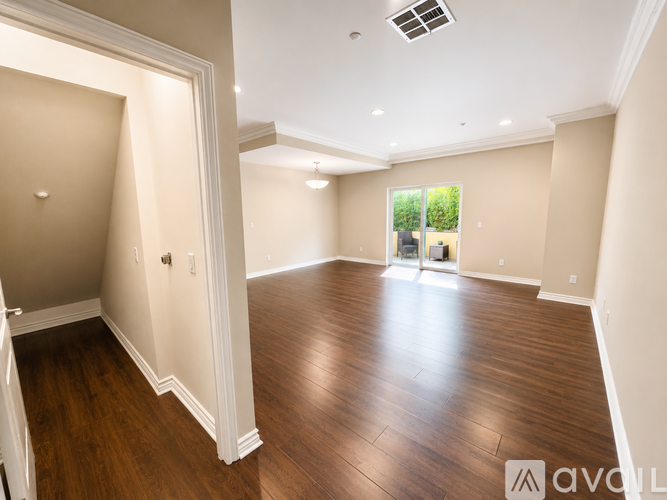 A spacious room with wooden flooring and white walls.