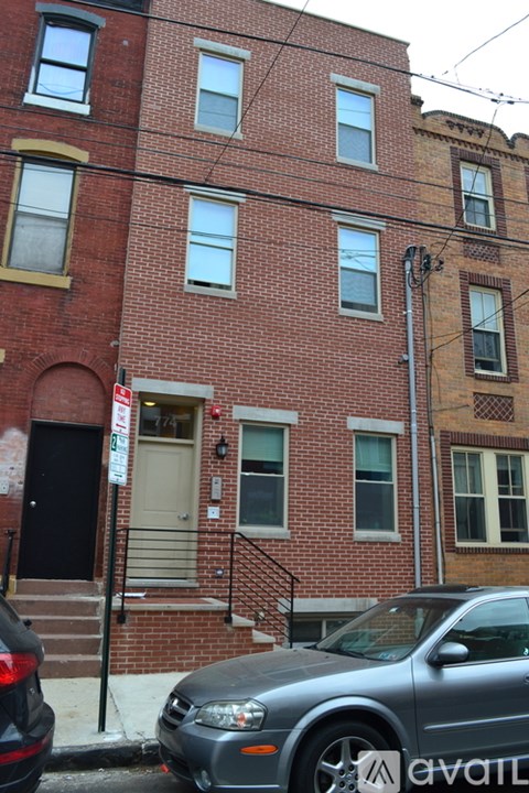 A grey car is parked in front of a red brick building.