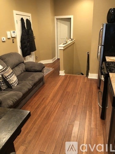 A living room with a grey couch and a black refrigerator.