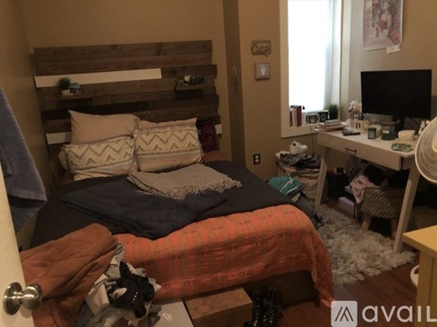 A bedroom with a bed, desk, and a window.