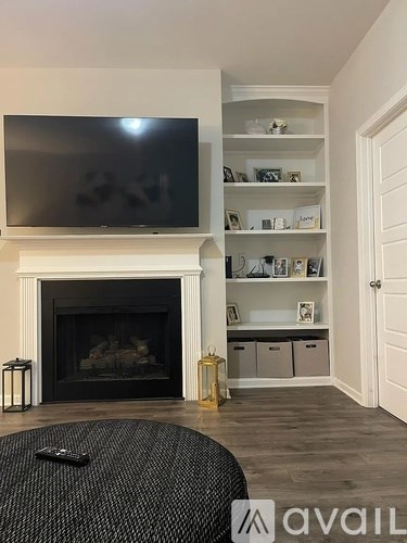 A living room with a fireplace and a television mounted above it.