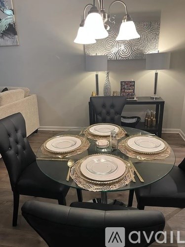 A dining room with a glass table and black chairs.