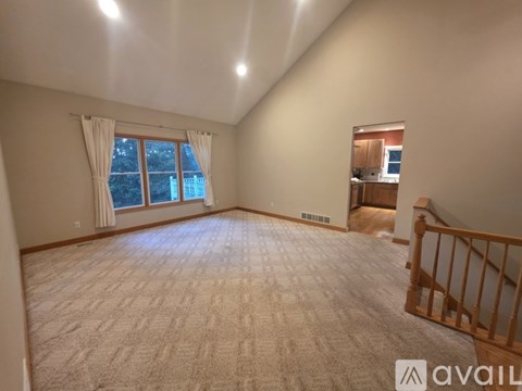 A spacious room with a carpeted floor and a window with curtains.