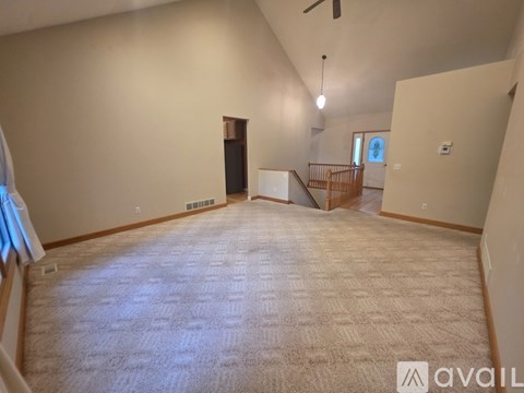 A spacious living room with a carpeted floor and a ceiling fan.