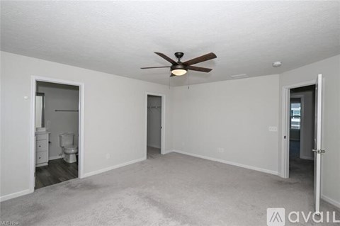 A spacious room with a ceiling fan and carpeted floor.