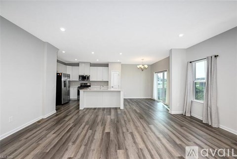 A spacious kitchen with wood flooring and white walls.