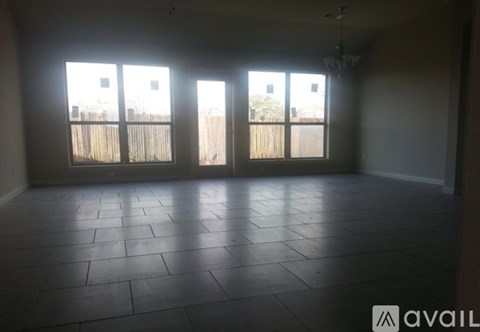 A room with tiled flooring and three windows.