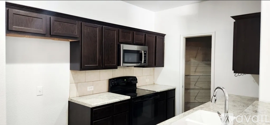 A kitchen with brown cabinets and black appliances.