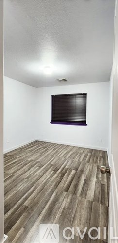 A room with wooden flooring and a window with blinds.