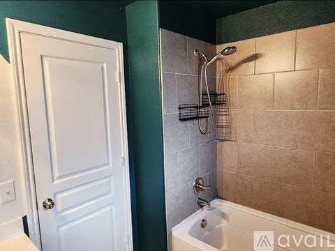A white door is next to a bathtub in a bathroom.
