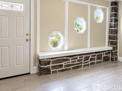 A white door is on the left of a wall with three windows.