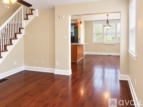 A spacious room with wooden floors and a staircase.