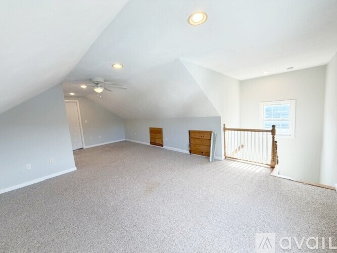 A spacious room with a ceiling fan and a door leading to a balcony.